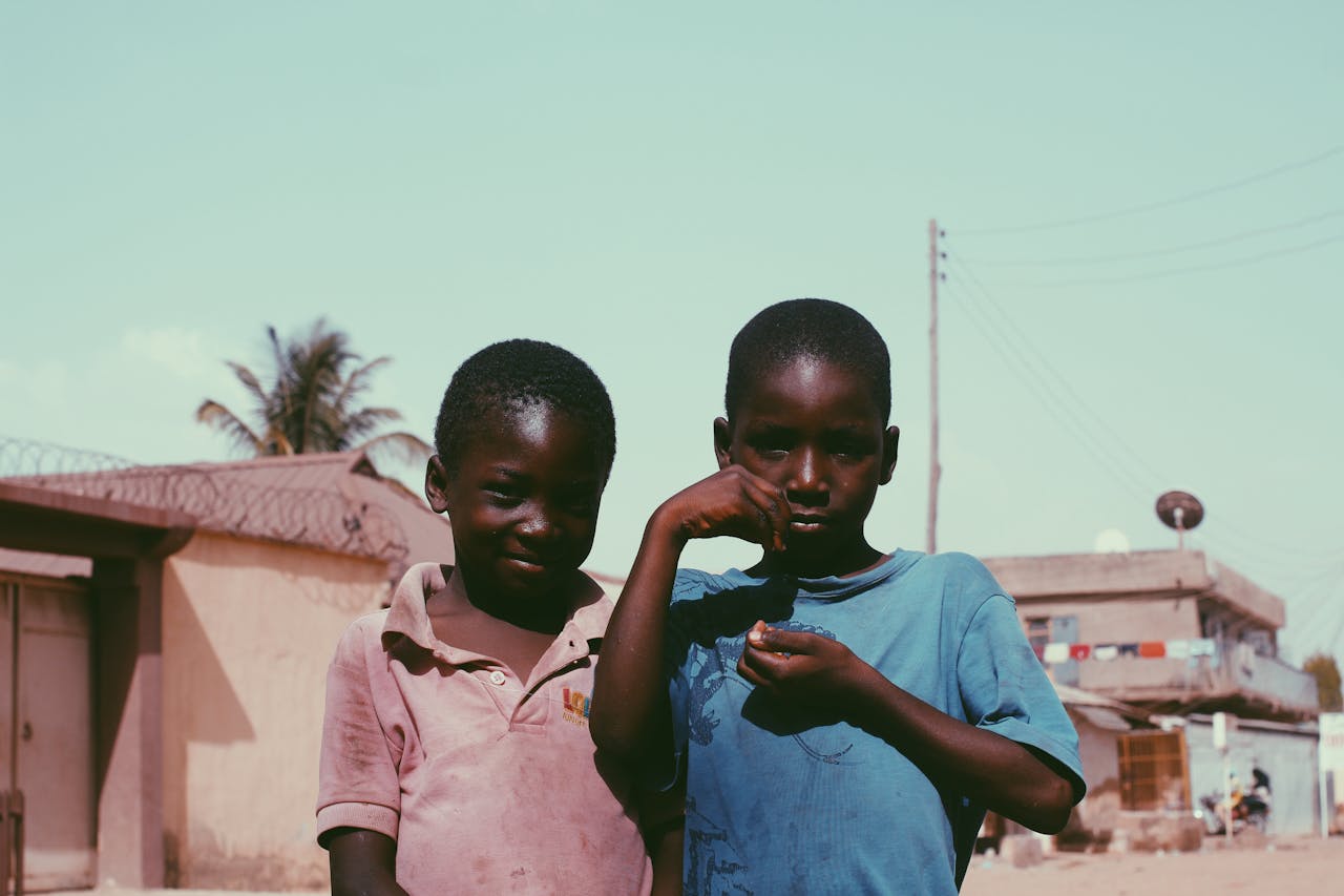 services-01 Two African boys smiling and posing outdoors, showcasing friendship in a rural setting.